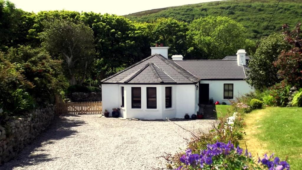 a small white house with a gravel driveway at Kilcommon Lodge Holiday Hostel in Belmullet