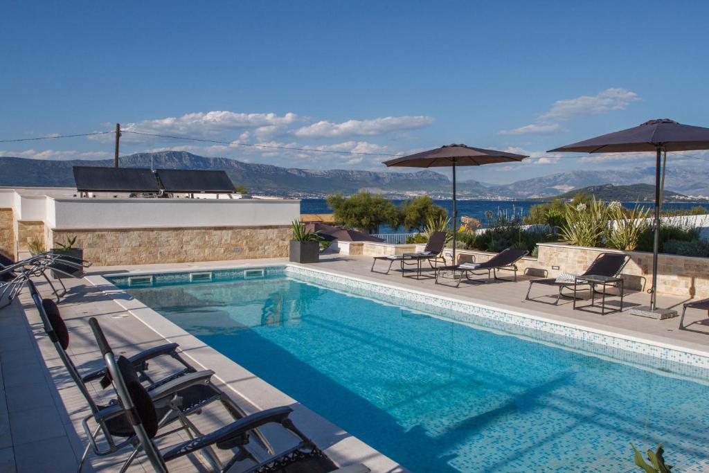 a swimming pool with chairs and umbrellas on a building at Luxury Poolside Villa in Slatine