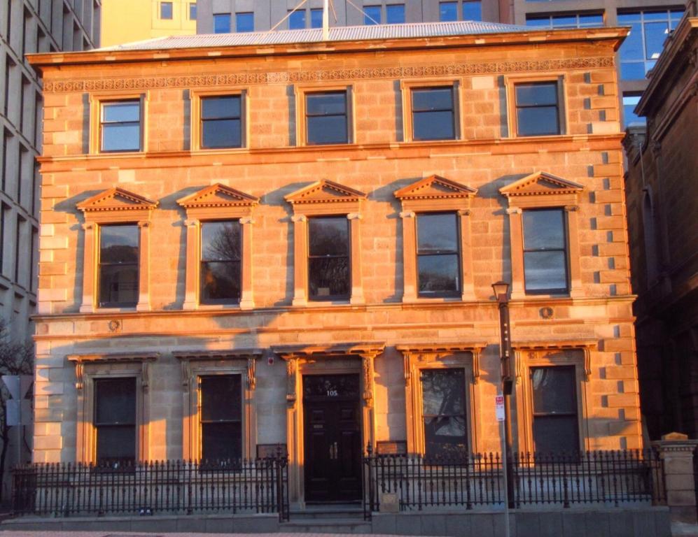 an orange brick building with a black door at 105 Mac Unique Apartments in Hobart