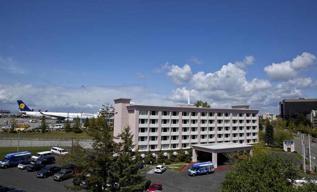 duży budynek z parkingiem i samolotem w obiekcie Coast Gateway Hotel w mieście SeaTac