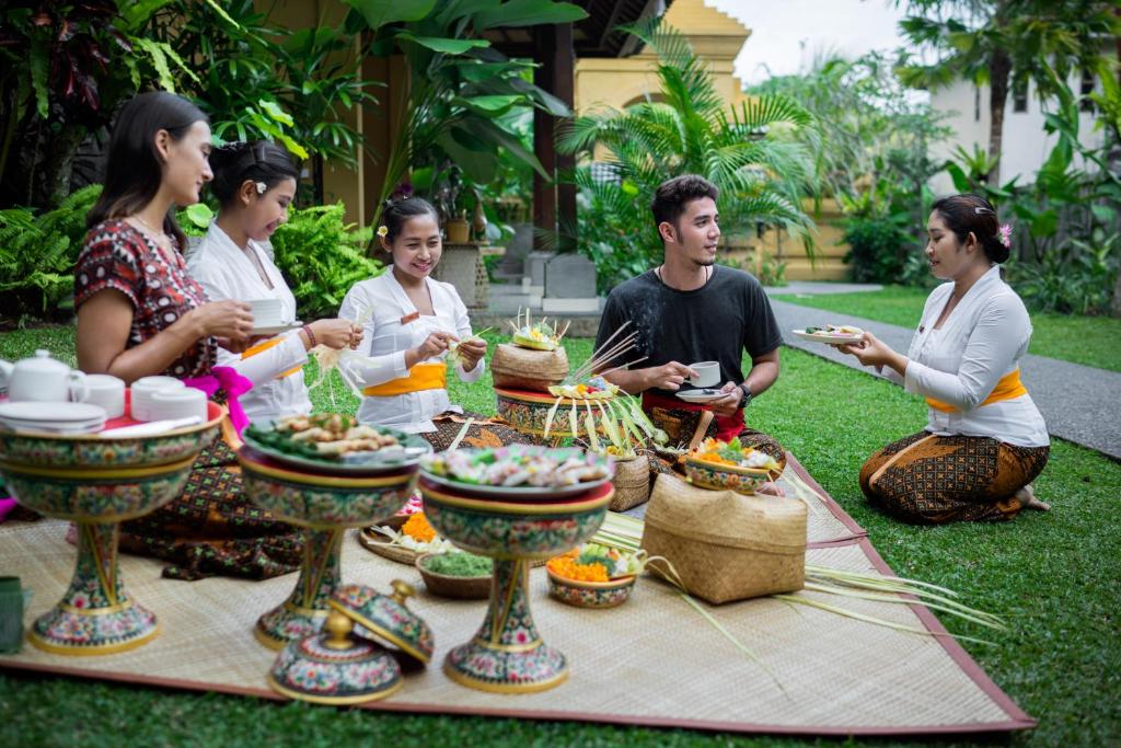 a group of people sitting around a table with food at Jati Cottage in Ubud