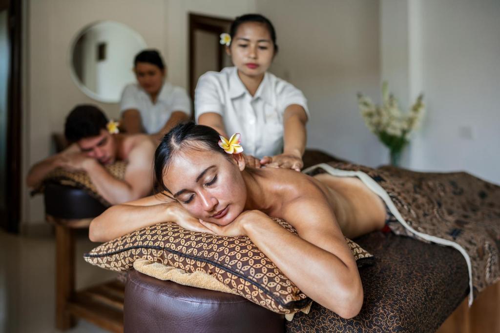 a woman laying on a bed getting a massage at Jati Cottage in Ubud
