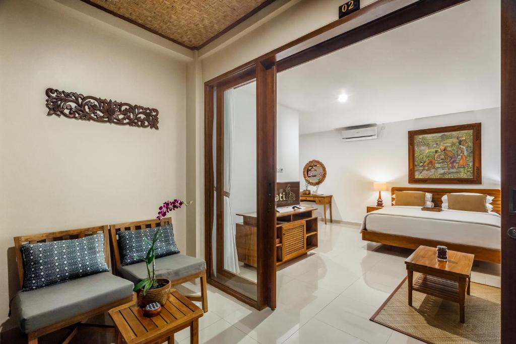 a bedroom with a bed and a couch and a table at Jati Cottage in Ubud