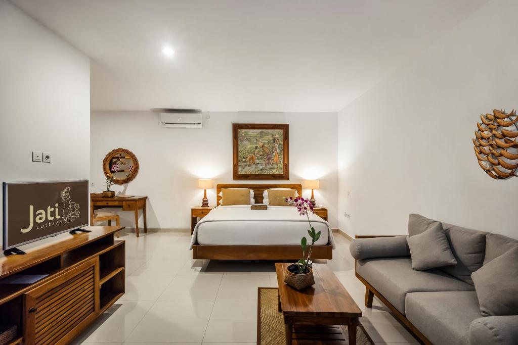 a hotel room with a bed and a couch at Jati Cottage in Ubud