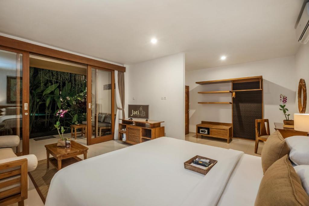 a bedroom with a bed and a living room at Jati Cottage in Ubud