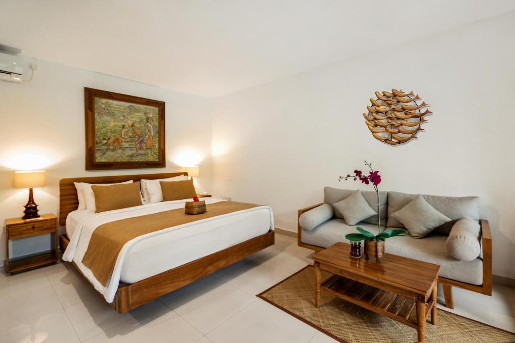 a bedroom with a large bed and a couch at Jati Cottage in Ubud