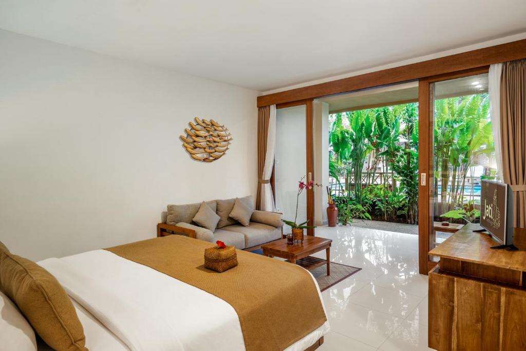 a bedroom with a bed and a couch and a television at Jati Cottage in Ubud