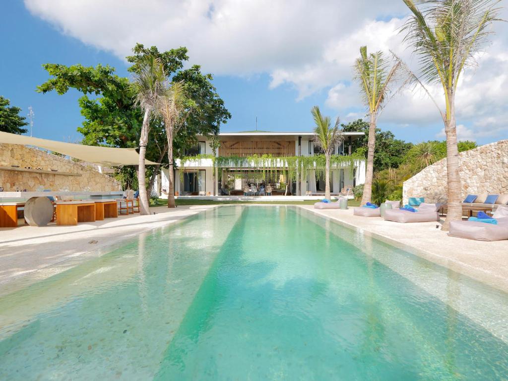 a swimming pool with palm trees and a building at Villa Seascape by Elite Havens in Nusa Lembongan