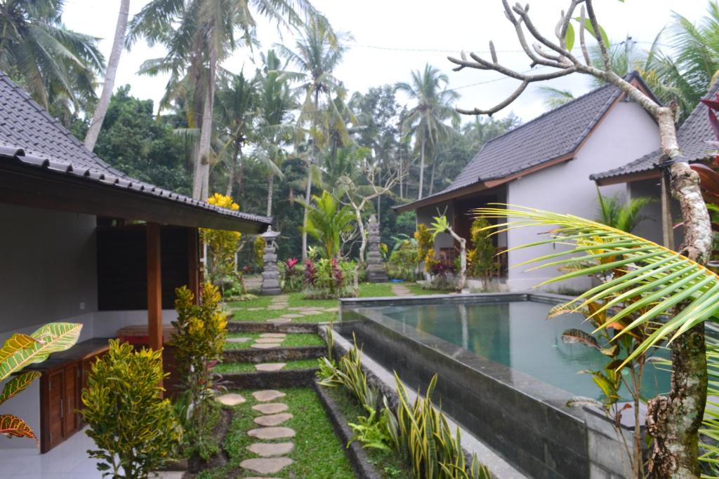 a villa with a swimming pool in front of a house at Buda Cottage Ubud in Ubud