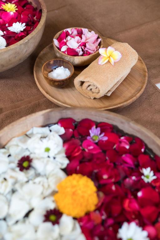 a table with three plates of flowers and bowls at Jati Cottage in Ubud