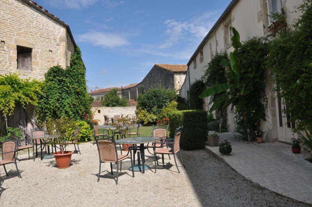 a patio with a table and chairs in a courtyard at Hôtel du Donjon in Aulnay