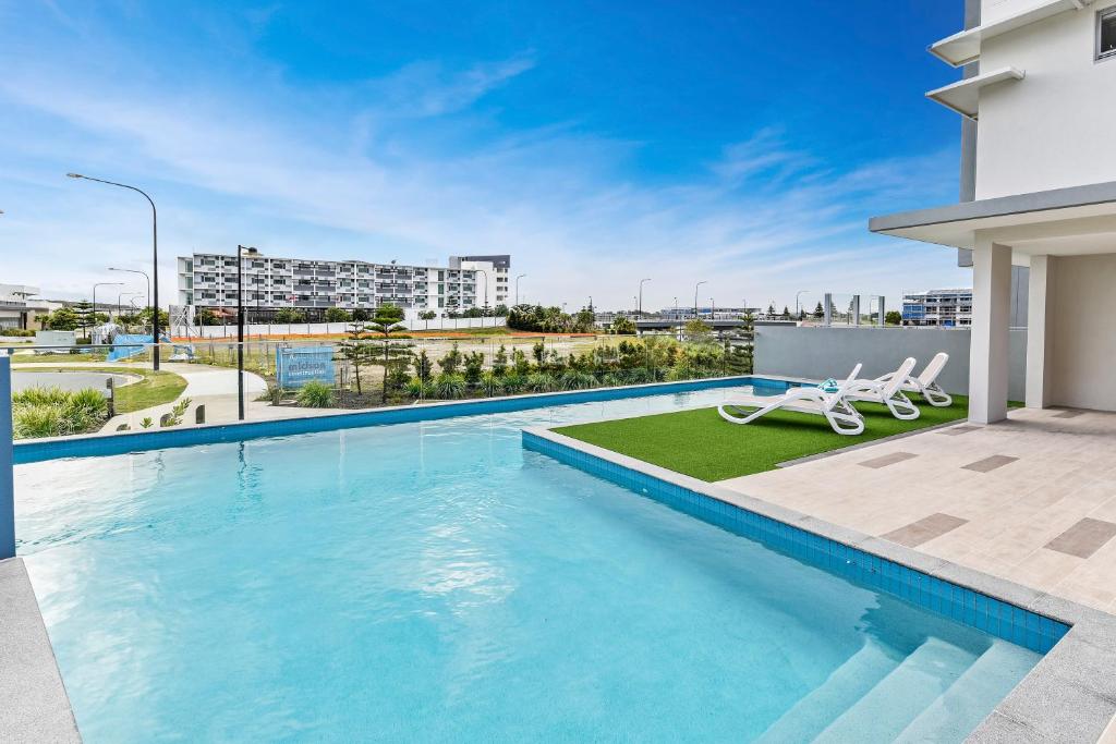 a swimming pool with two lounge chairs on a building at Aquarius Kawana in Kawana Waters