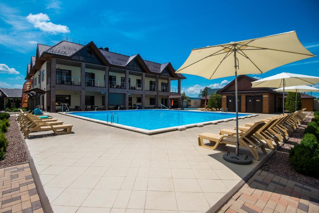 a swimming pool with chairs and an umbrella at Rasputin Hotel in Mostovskoy
