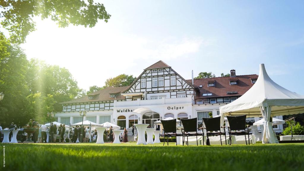 a white building with tables and chairs in front of it at Waldhaus Oelper in Braunschweig