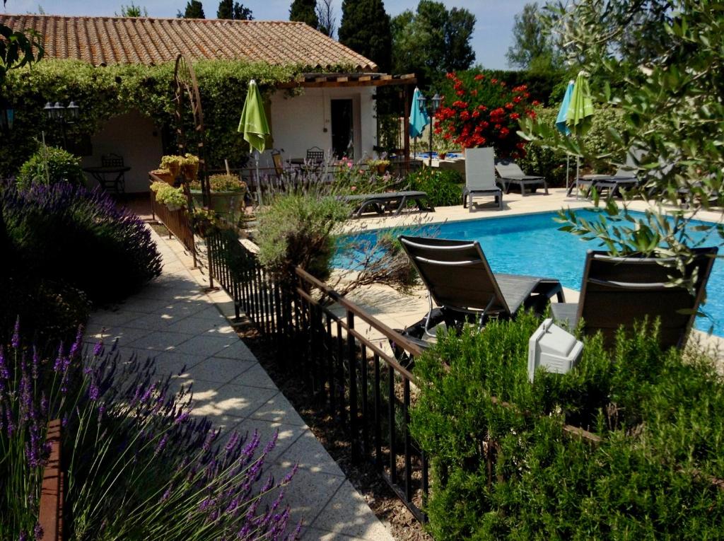 una piscina en un patio con sillas y sombrillas en Logis Hotel Restaurant Hostellerie de la Tour, en Fontvieille
