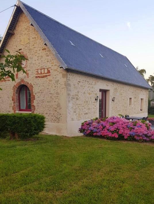 une maison avec des fleurs violettes devant dans l'établissement Le Gite de l'Etrier, à Canchy