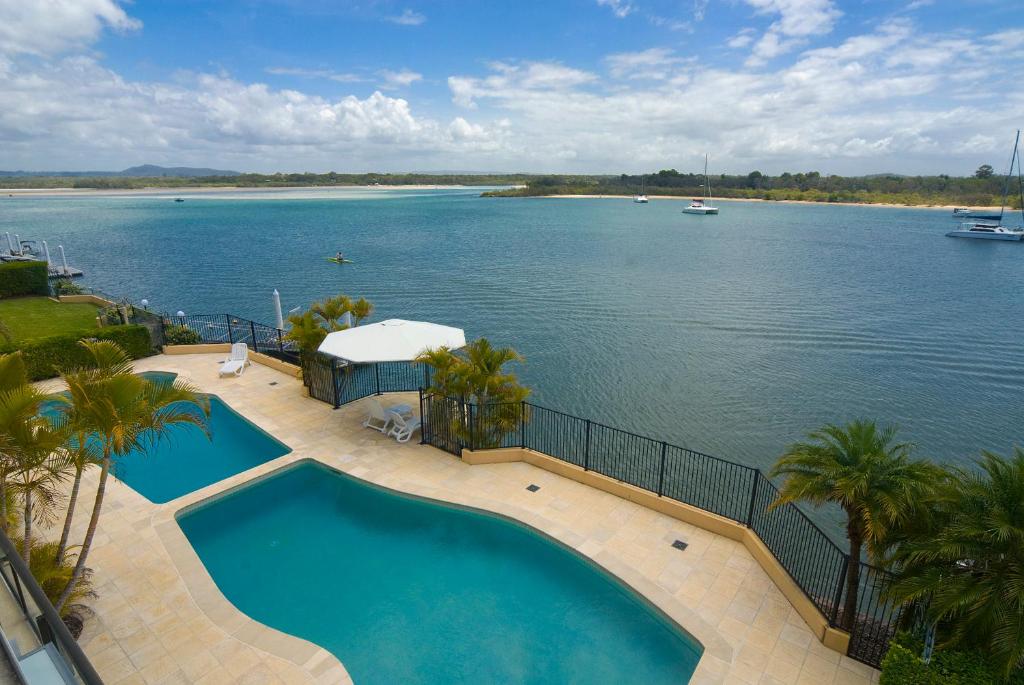 een zwembad met uitzicht op een waterlichaam bij Commodore Apartments in Noosa Heads