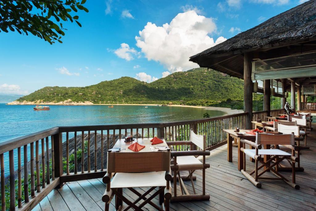 a restaurant with tables and chairs on a deck overlooking the ocean at Six Senses Ninh Van Bay in Ninh Van Bay