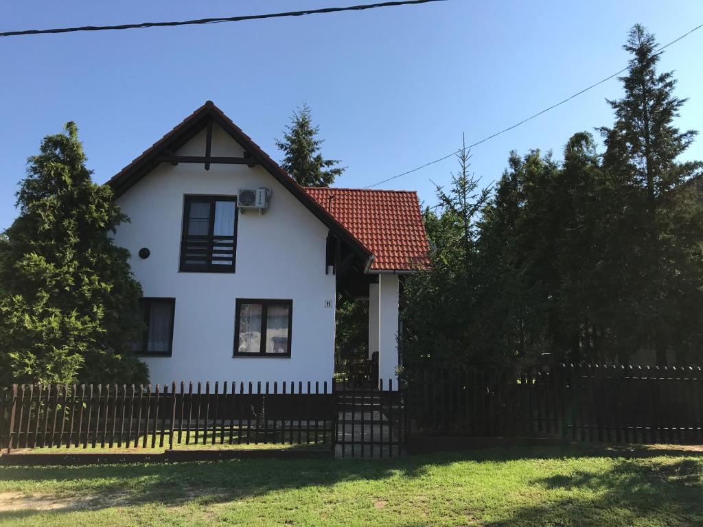 biały dom z płotem i drzewami w obiekcie Lovas Vendégház w mieście Tiszafüred