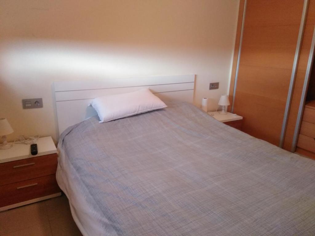 Un dormitorio con una cama con una almohada blanca. en Apartamento en residencial arenas San Juan en Alicante