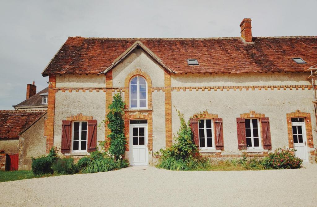 an old brick house with a white door and windows at gîte du château in La Bussière