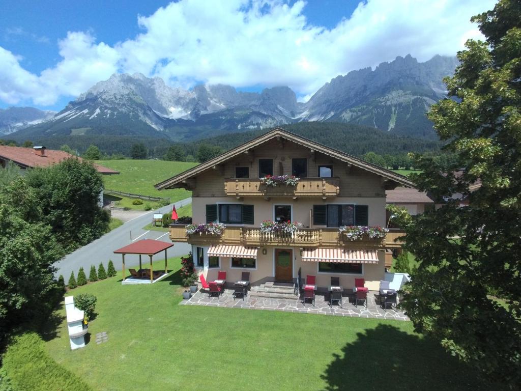 a house with a balcony and mountains in the background at Haus Drei Linden in Going am Wilden Kaiser