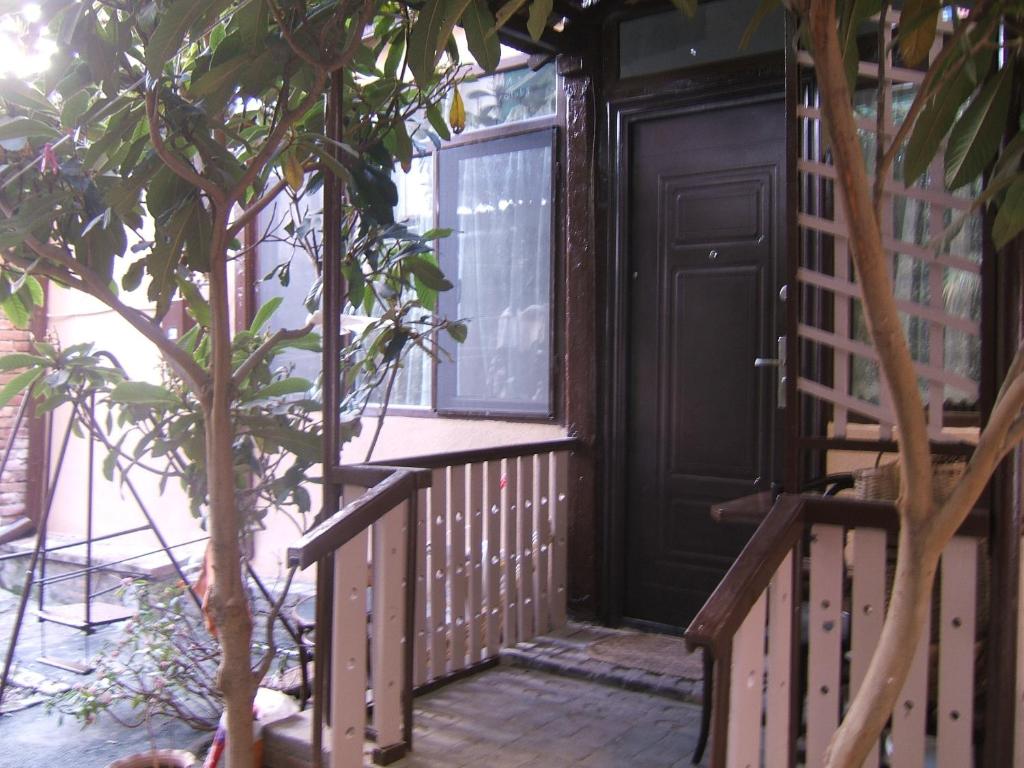 eine Holzterrasse mit einer Tür und einem Baum in der Unterkunft Tina's Homestay in Tbilisi City