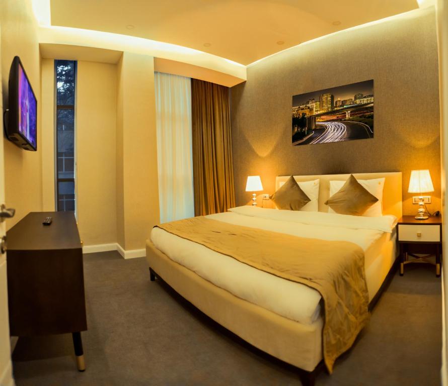 a hotel room with a large bed and a television at Aksent Hotel in Baku