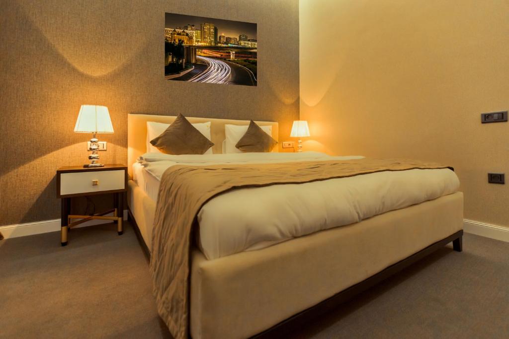 a bedroom with a bed and a nightstand with two lamps at Aksent Hotel in Baku