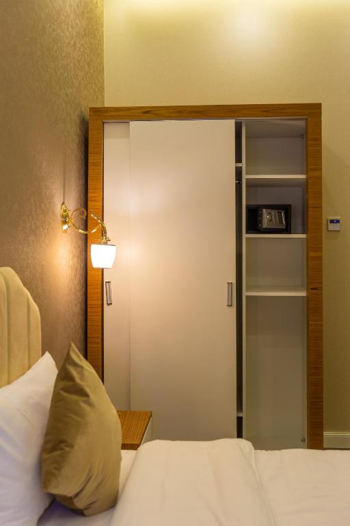 a bedroom with a white bed with a glass door at Aksent Hotel in Baku