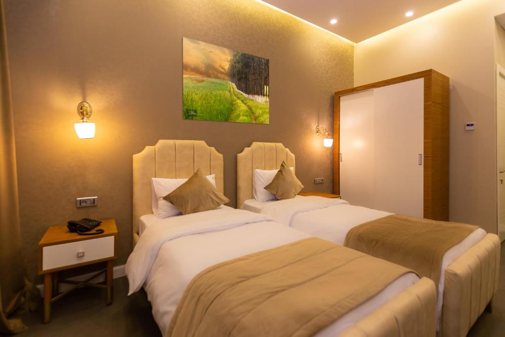 a hotel room with two beds and a mirror at Aksent Hotel in Baku