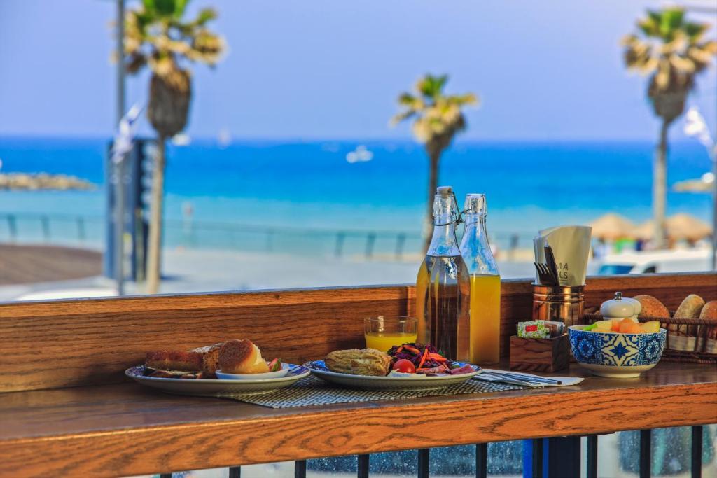 a table with plates of food and drinks and the beach at Prima Tel Aviv Hotel in Tel Aviv