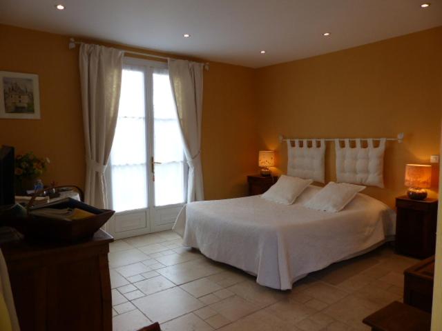 a bedroom with a white bed and a large window at Les Amandines in Chisseaux