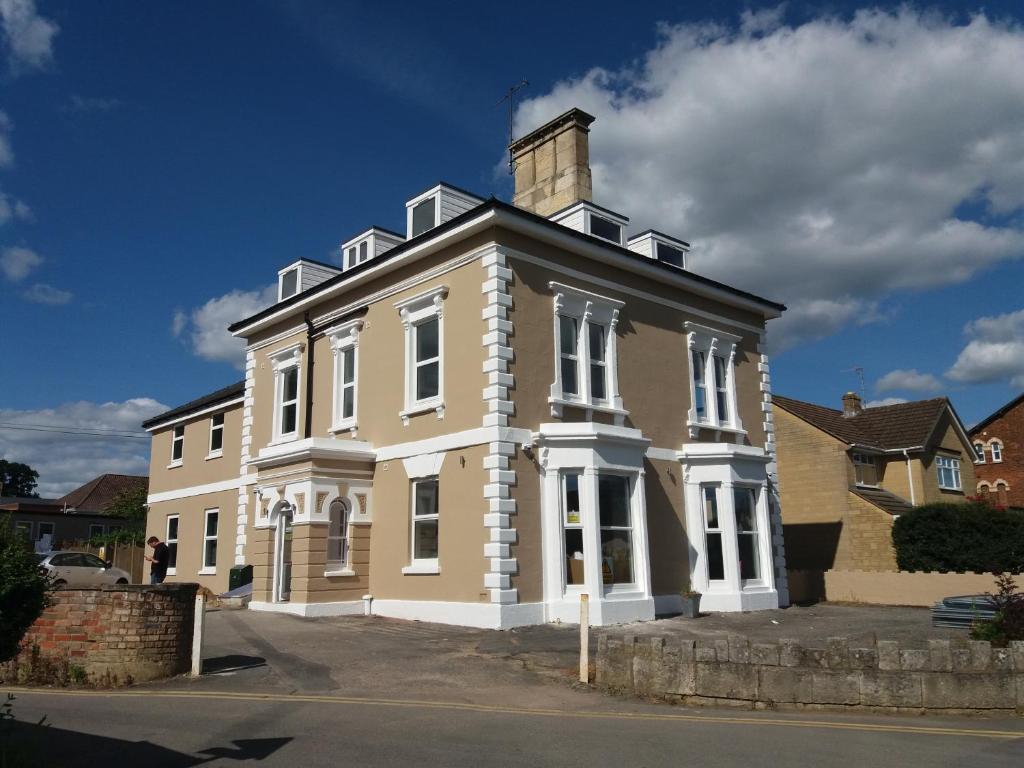 een groot geel huis met een schoorsteen bovenop bij Cotswold Aparthotel in Stroud