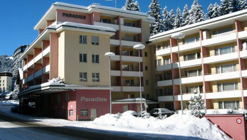 een groot gebouw met sneeuw ervoor bij Paradies 001 in Arosa