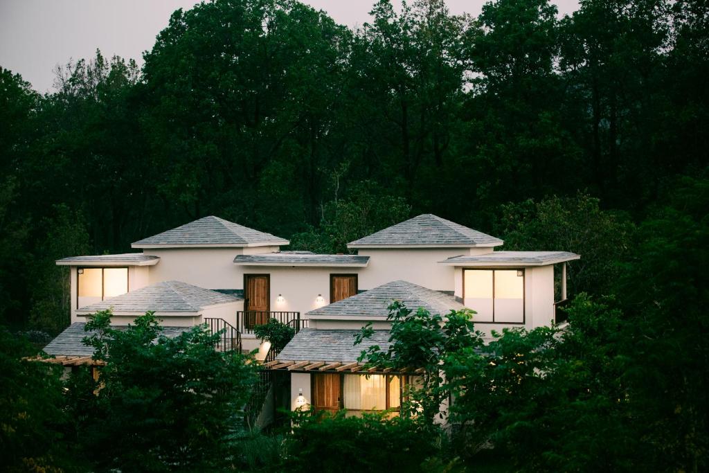 a large white house with trees in front of it at Saraca Resort & Spa Corbett in Garjia