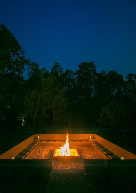 a fire pit in a garden at night at Saraca Resort & Spa Corbett in Garjia