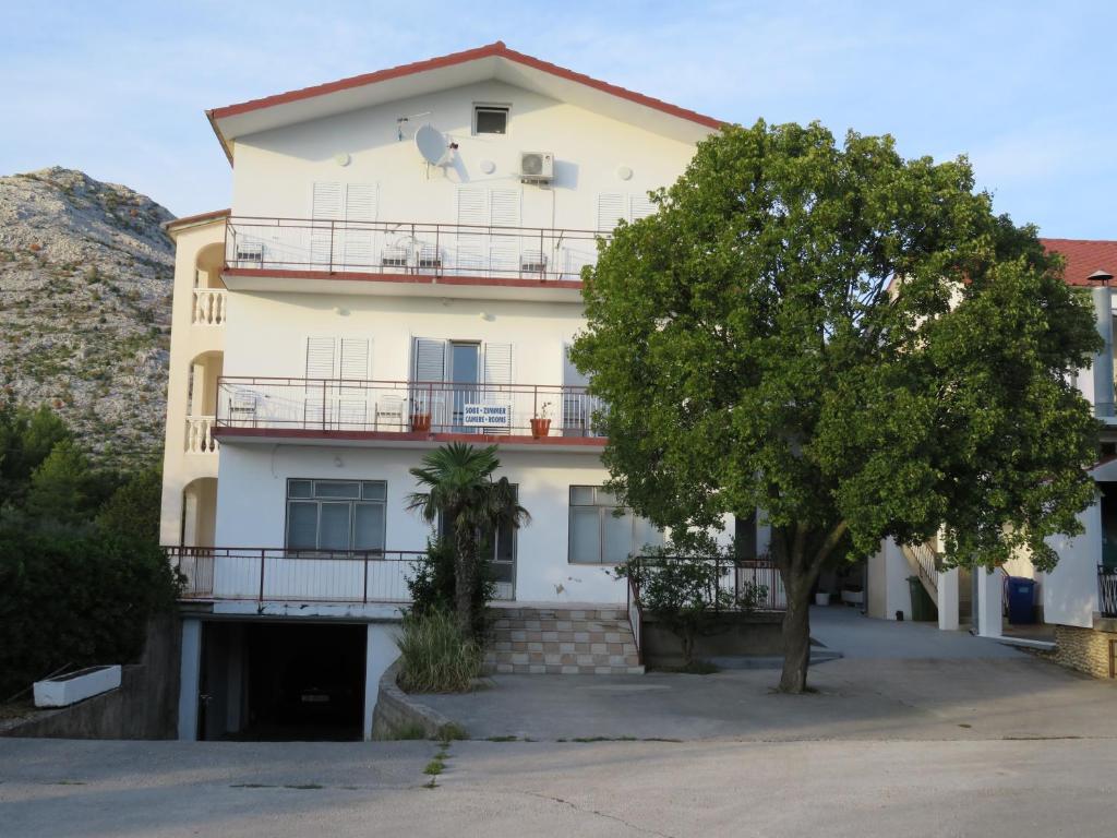 a large white building with a tree in front of it at Apartmani MM in Starigrad-Paklenica