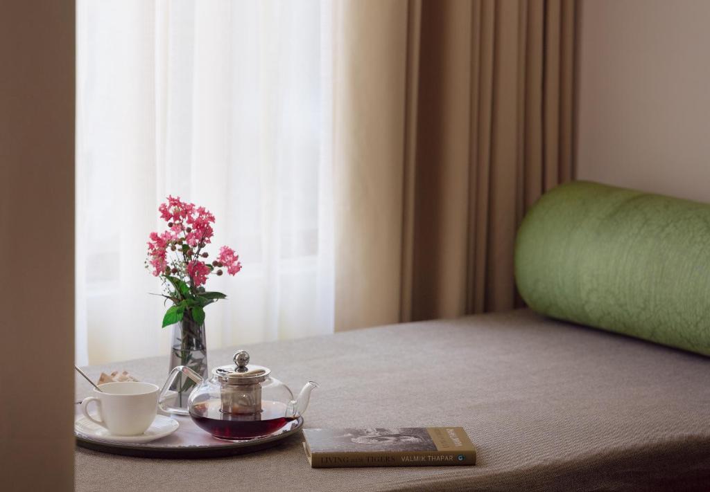 a table with a plate with a vase of flowers and a cup at Saraca Resort & Spa Corbett in Garjia