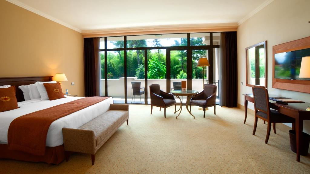 a hotel room with a bed and a table and chairs at Kobuleti Georgia Palace Hotel & Spa in Kobuleti