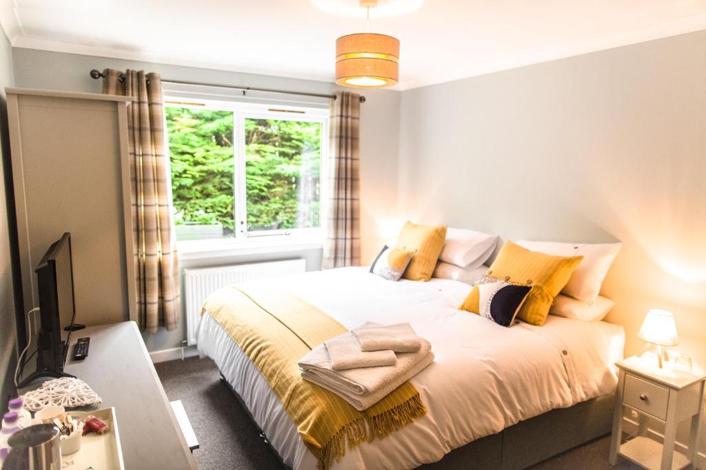 Un dormitorio con una cama con almohadas amarillas y una ventana en The Forge Bed & Breakfast, en Auchterarder