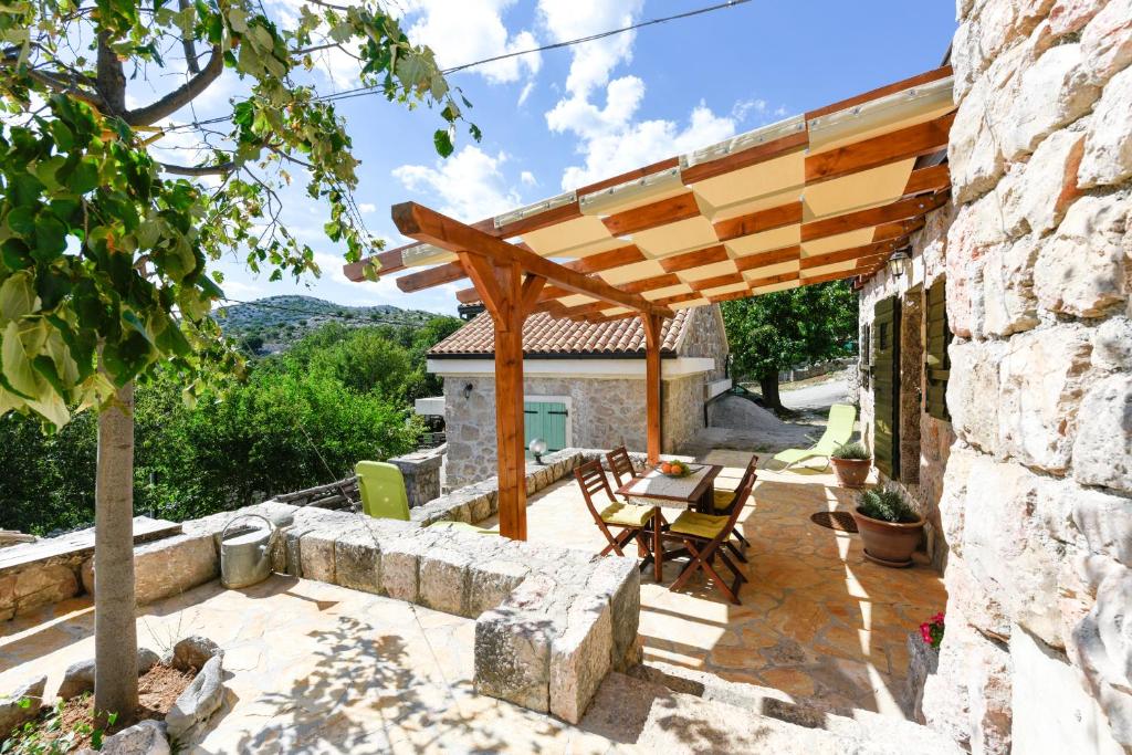 eine Terrasse mit einer hölzernen Pergola sowie einem Tisch und Stühlen in der Unterkunft Stone house BURA in Tribanj-Krušćica