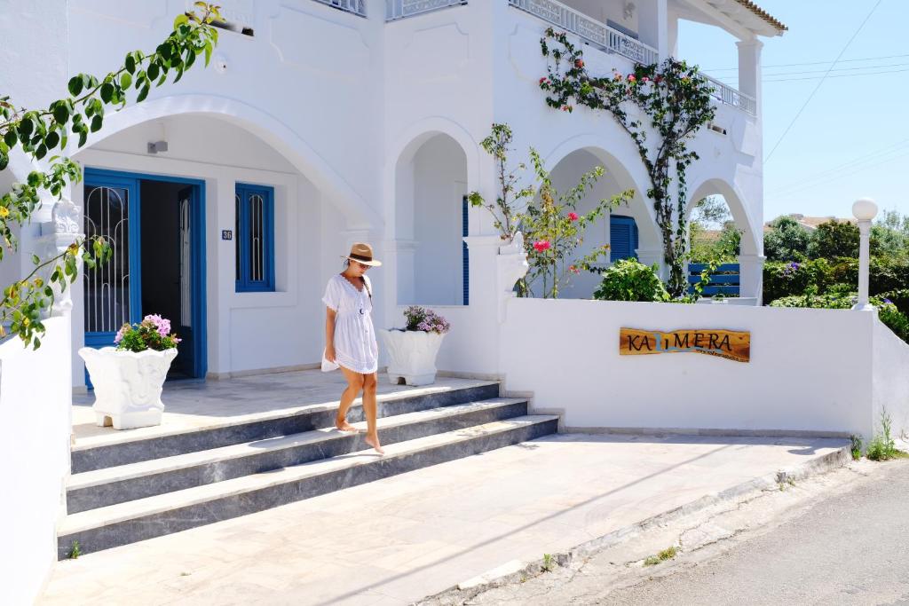 Una mujer subiendo las escaleras a una casa blanca en Kalimera Studios and Apartments en Moraitika