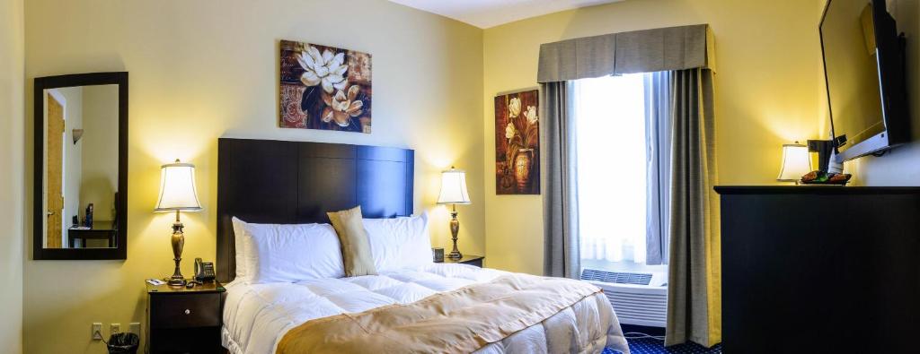 um quarto com uma cama grande e uma janela grande em Asbury Inn & Suites em Wilmore