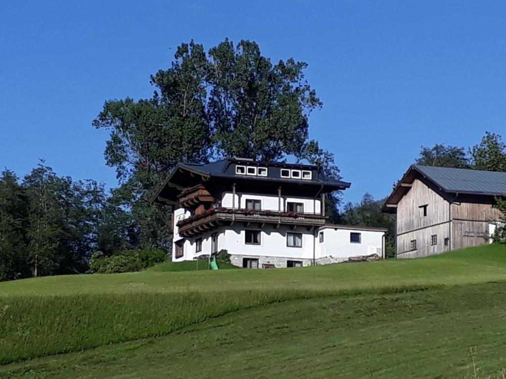 una gran casa blanca en una colina con un granero en Appartement Wildkogelblick, en Neukirchen am Großvenediger