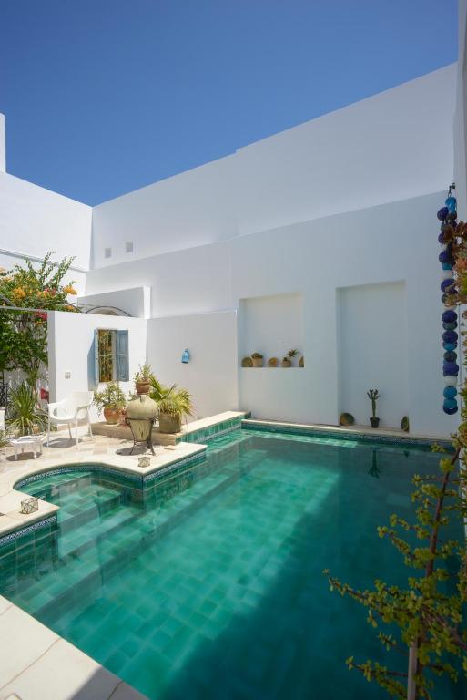 een zwembad met blauw water in een huis bij Dar R'Bat, Maison d'Hôtes de charme in Nabeul