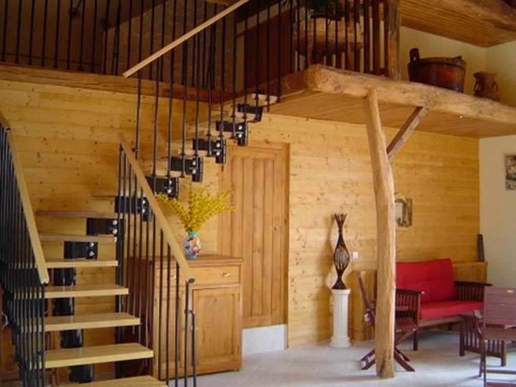 uma sala de estar com uma escada numa casa de madeira em Chambres d 'hôtes "Au vieux Préssoir" em Belley