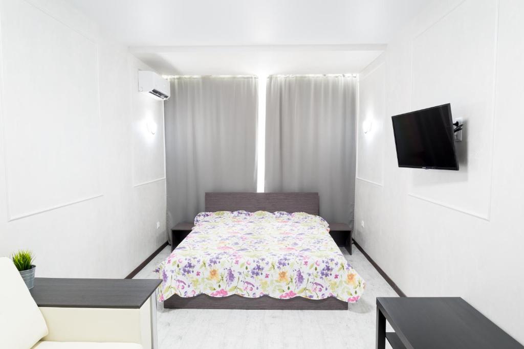 クルガンにあるApartment in Kurganのベッド1台、テレビが備わる小さな白い客室です。
