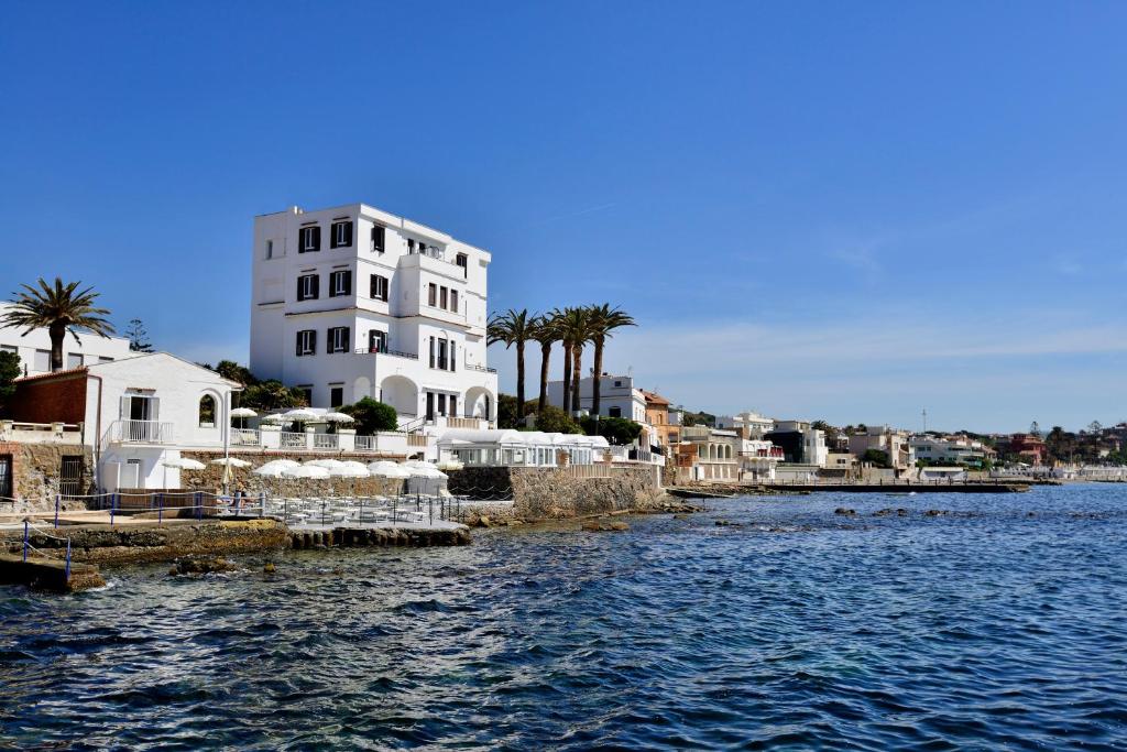a large white building next to a body of water at Villa delle Palme in Santa Marinella