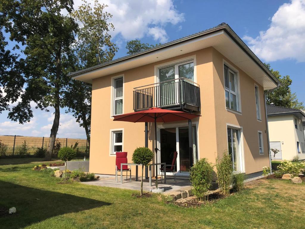 ein Haus mit einem Balkon und zwei Stühlen im Hof in der Unterkunft Ferienhaus Seerose in Hohenfelden